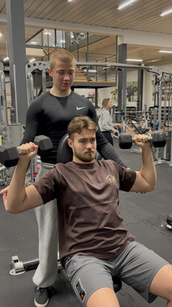 Trener personalny Warszawa podczas treningu barków z podopiecznym na siłowni CityFit Wiatraczna