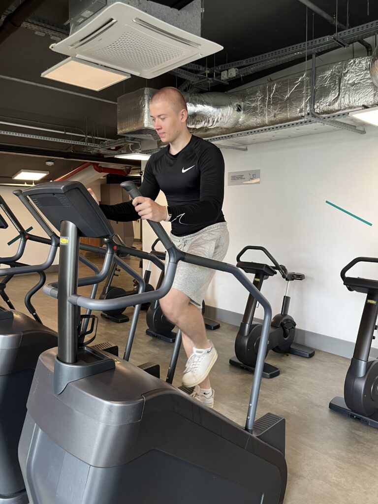 Trener personalny Adrian Wyszomirski podczas treningu cardio na schodach w CityFit Wiatraczna w Warszawie – przykład aktywności w procesie odzyskiwania męskości po 30.