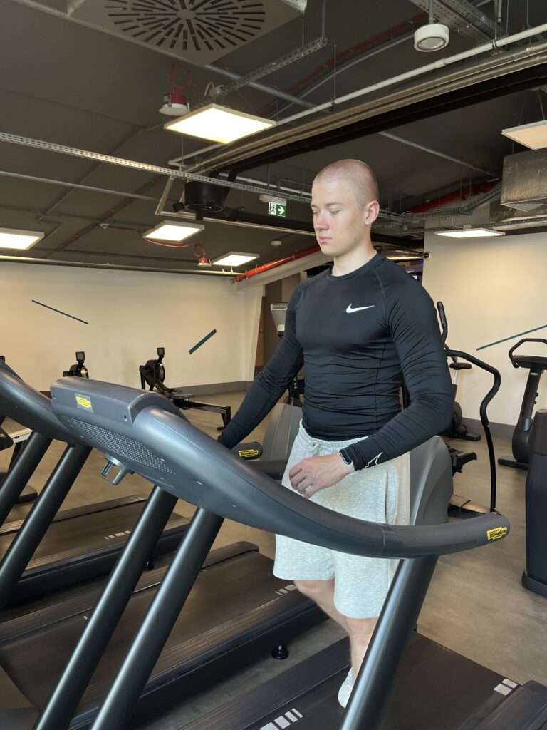 Adrian Wyszomirski wykonuje trening FBW 2 razy w tygodniu na siłowni podczas rozgrzewki na bieżni